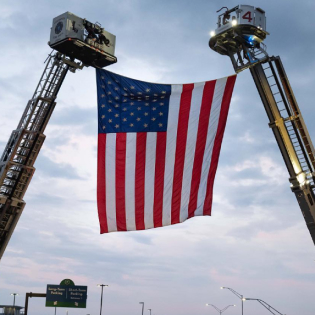American Flag raised by firetruck ladders